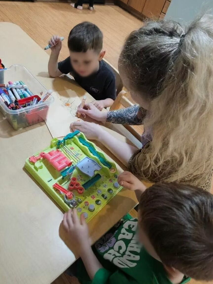 Children playing with a colorful board game at a table indoors