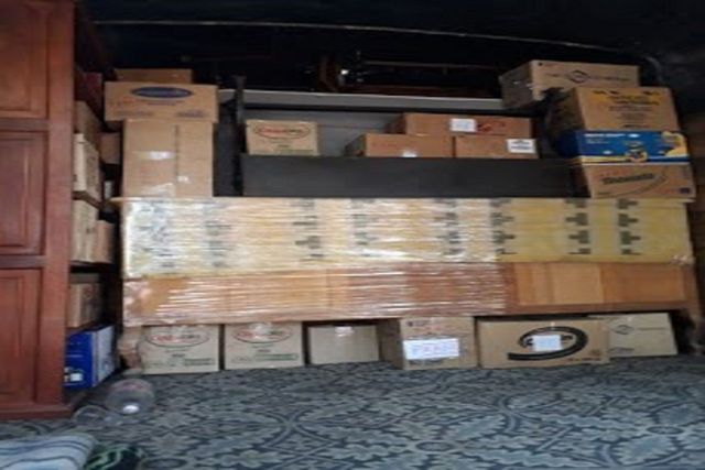 Armario de almacenamiento lleno de cajas de cartón apiladas y paquetes envueltos en estantes y en el suelo.