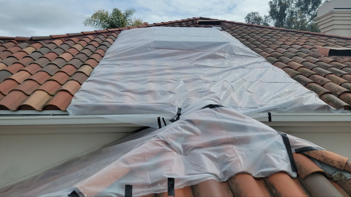 Plastic sheeting covers roof damage on a tiled house roof