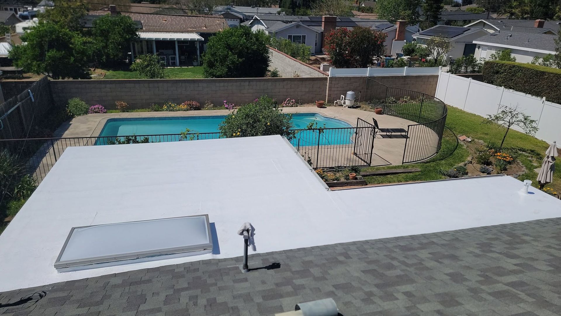 Rooftop patio with a large white deck, pool, hot tub, and a person standing near the edge.