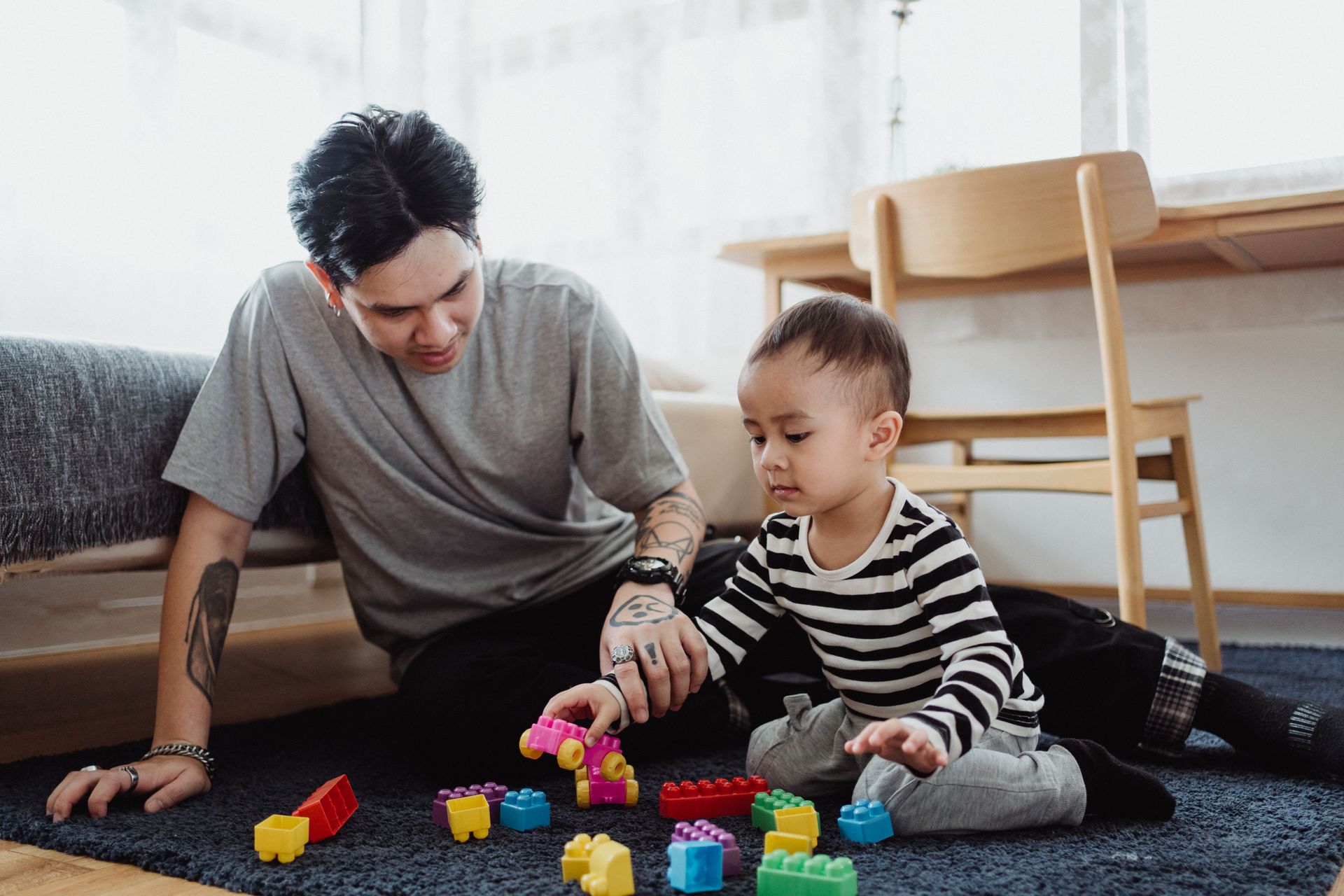 A man and young child playing with colour blocks