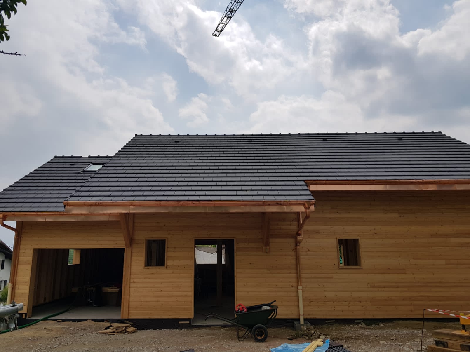 Une maison en bois avec un toit noir est en construction.