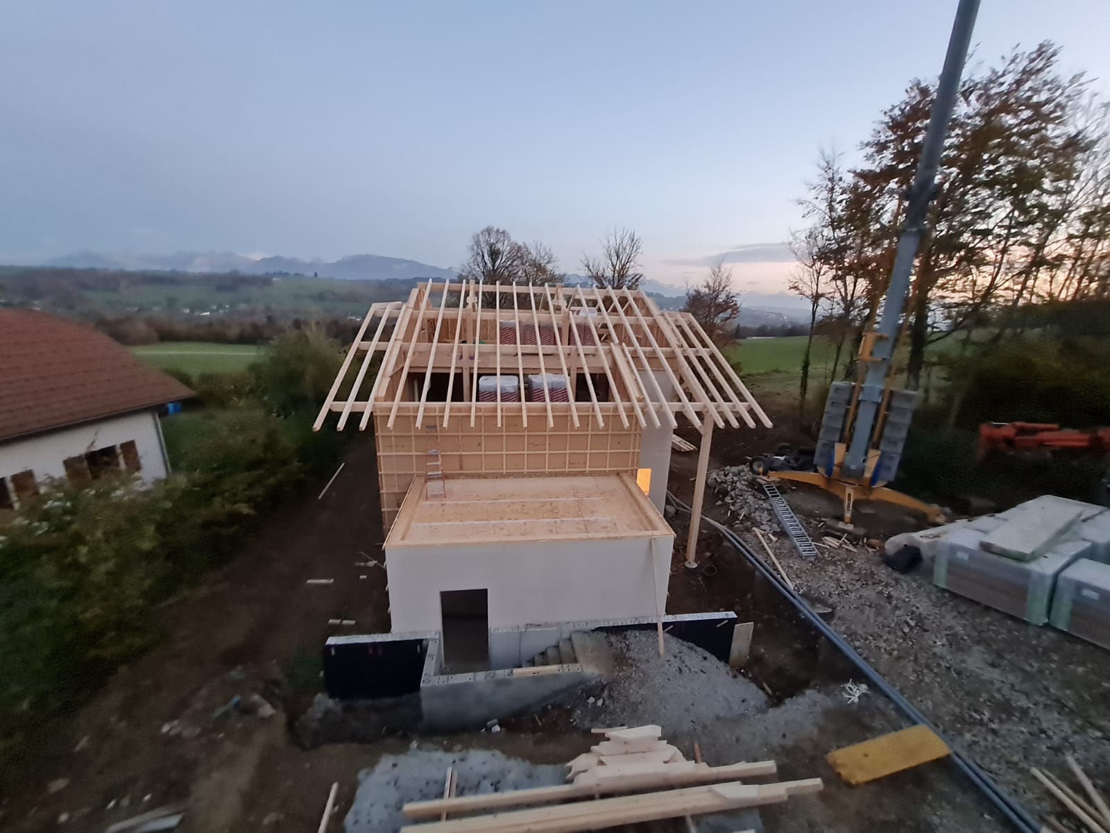 Une vue aérienne d'une maison en construction avec une grue en arrière-plan.