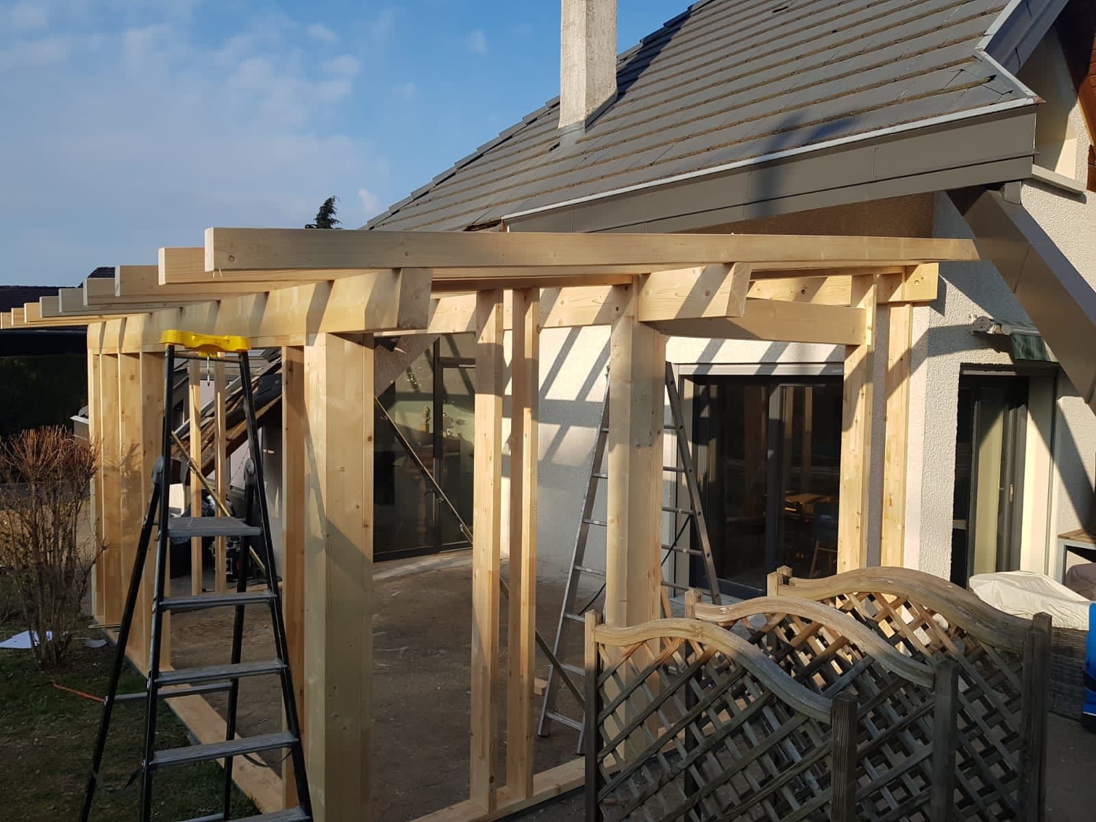 Une structure en bois est en construction devant une maison