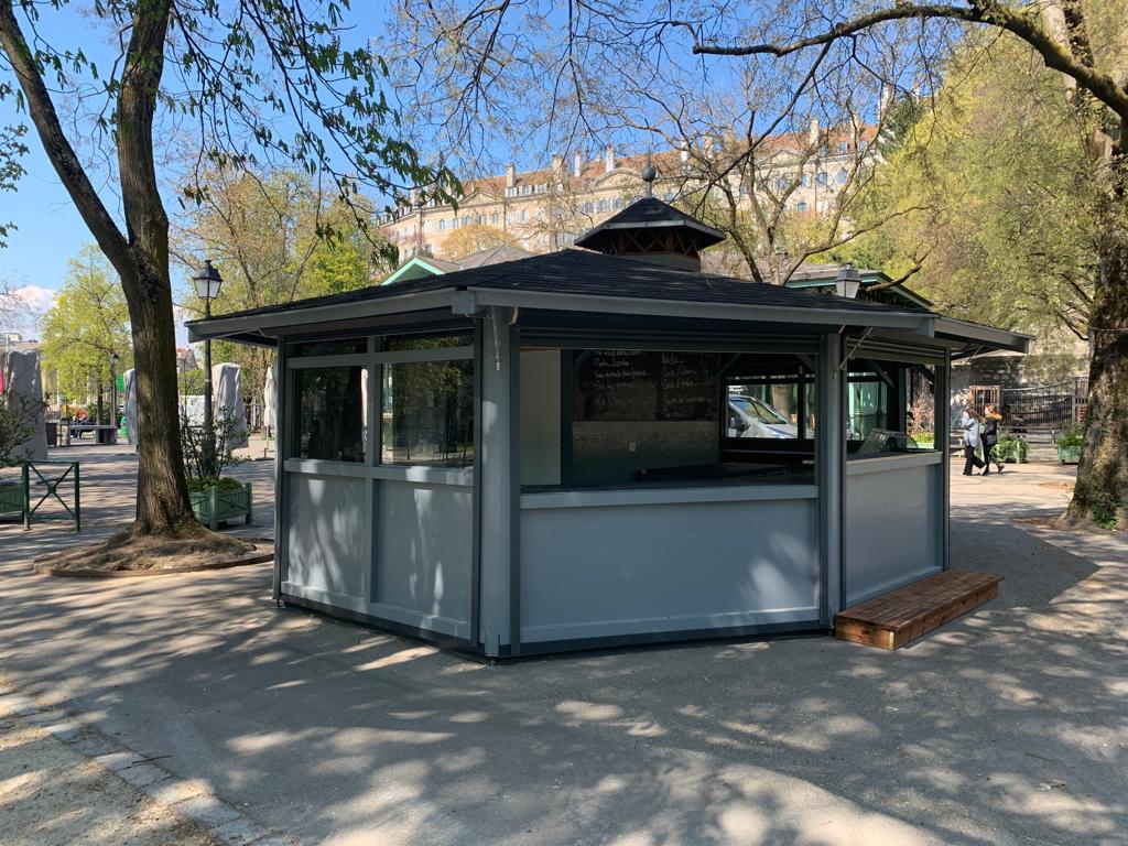 Un petit bâtiment se trouve au milieu d'un parc entouré d'arbres.