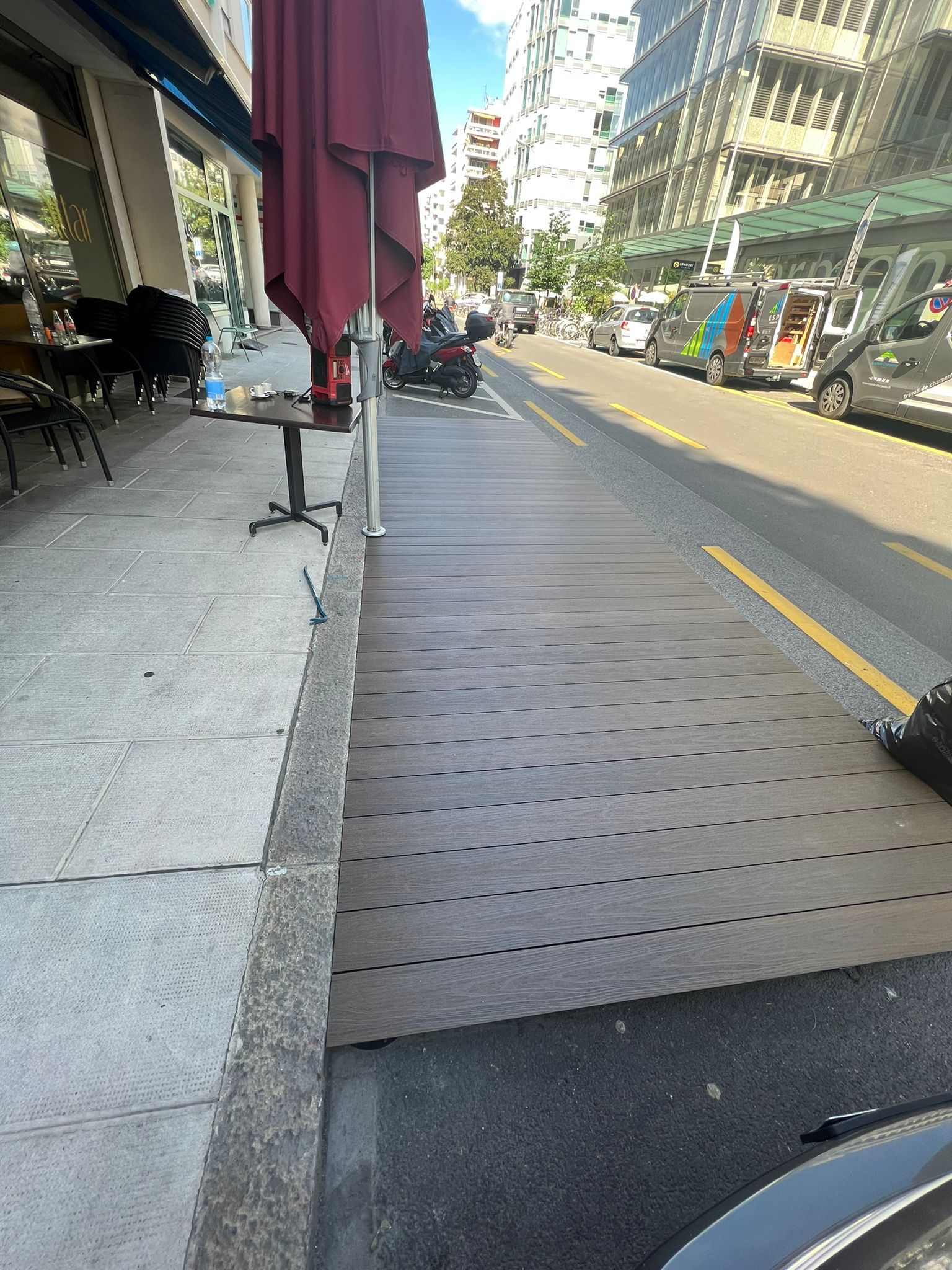 Un trottoir avec des tables et des parasols à côté d'une rue.