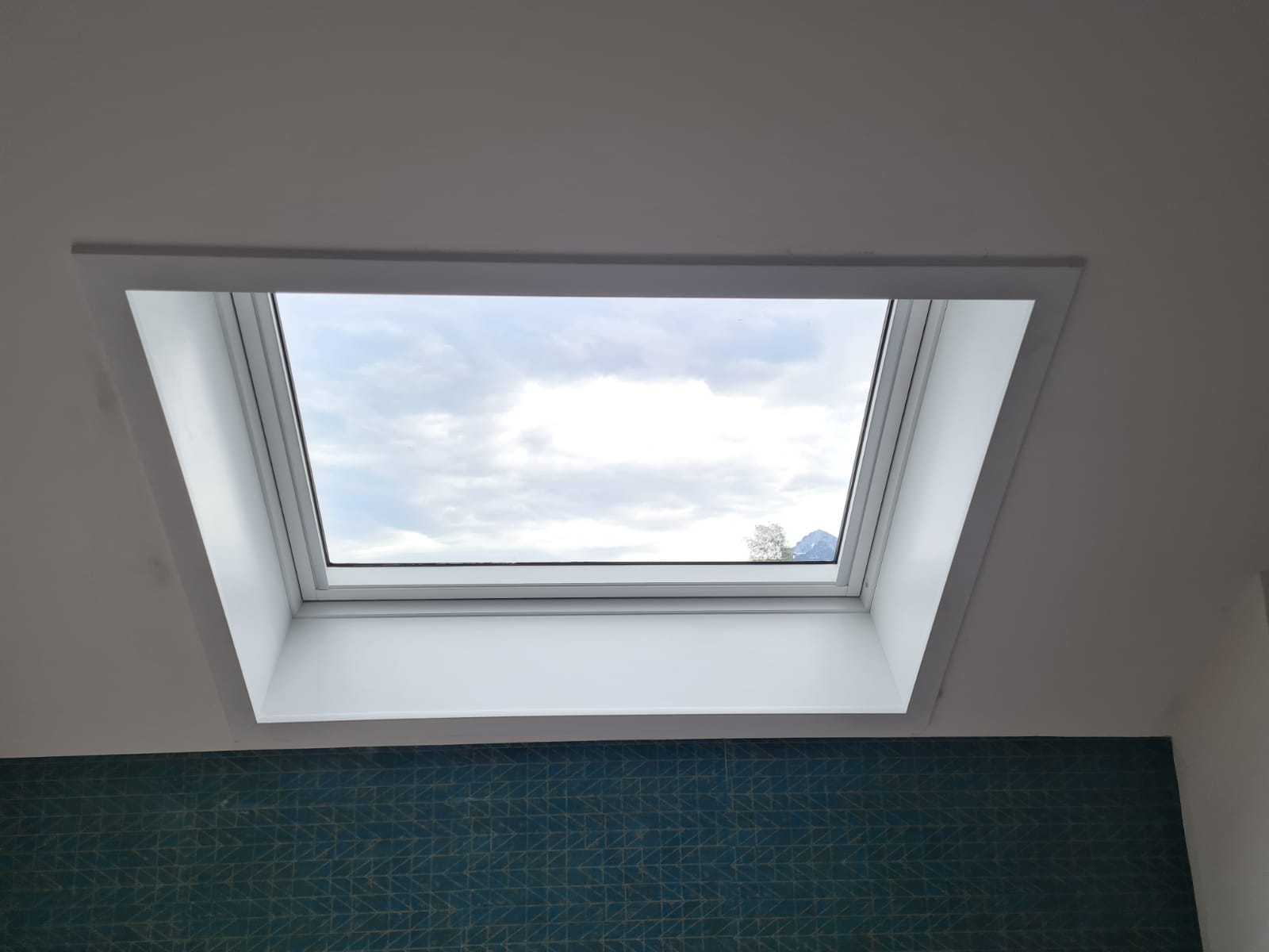 Une lucarne dans une pièce avec un mur bleu