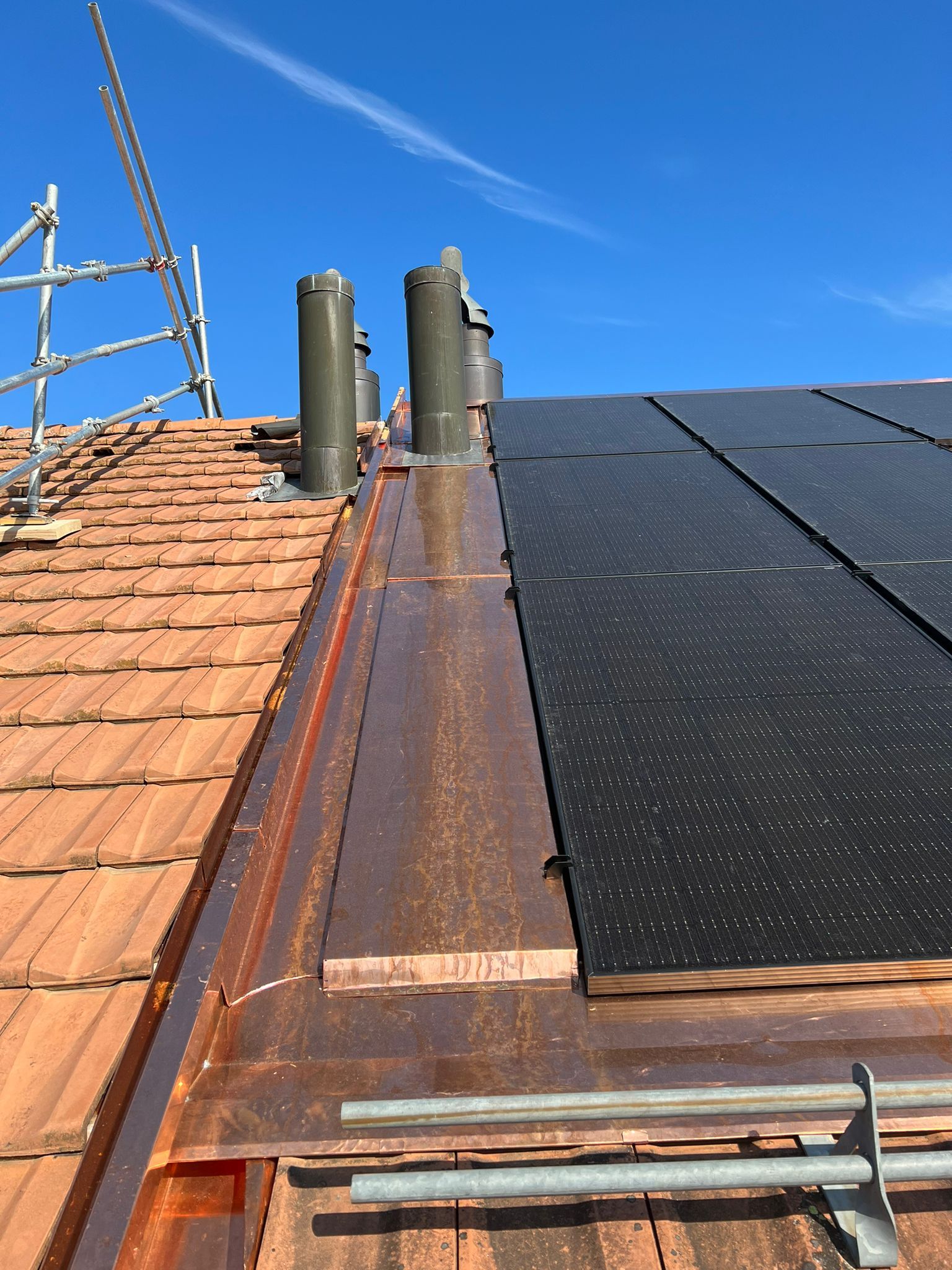 Un toit avec des panneaux solaires et des cheminées dessus