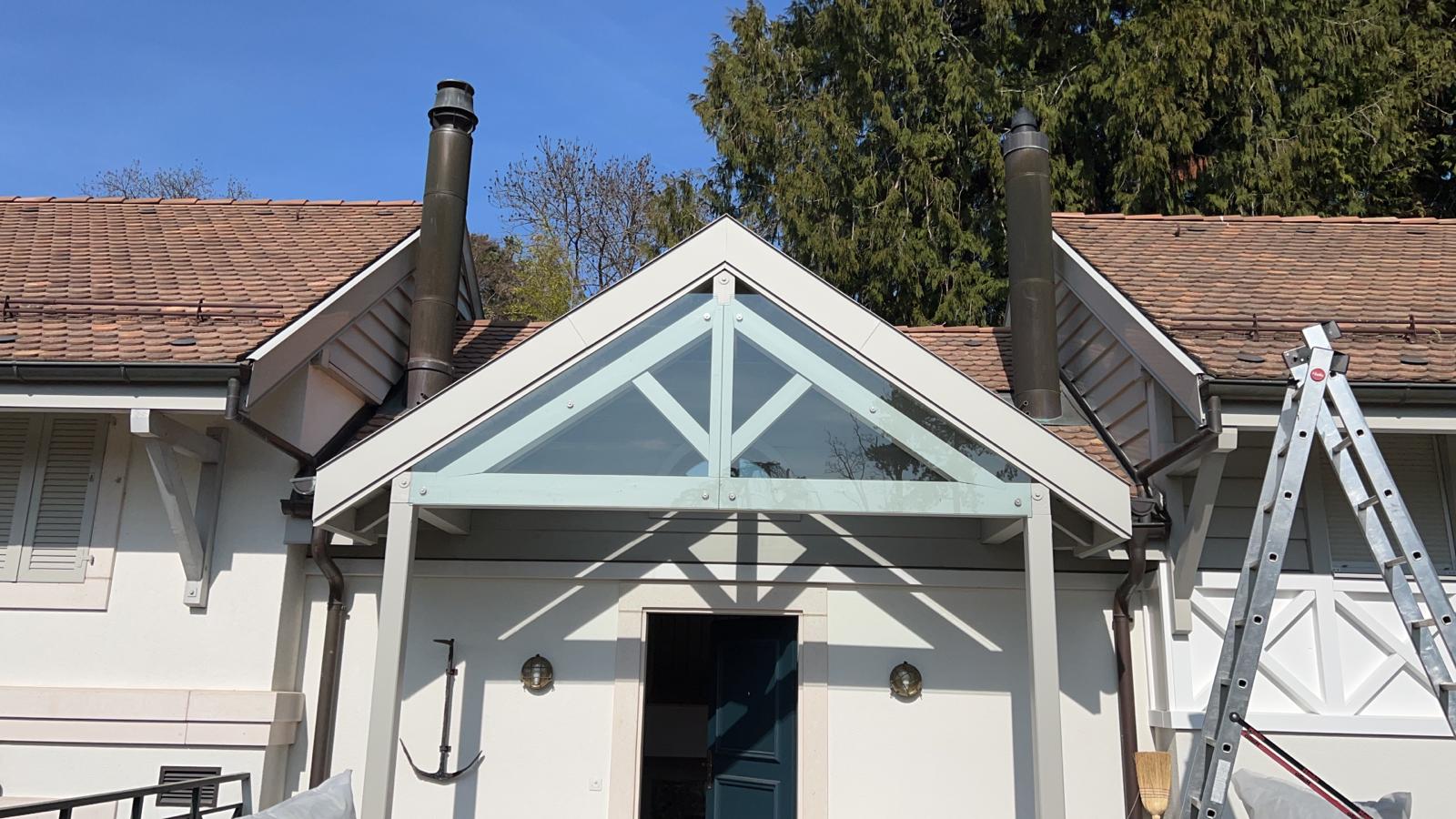 Une maison blanche avec un porche en bois et une échelle devant.