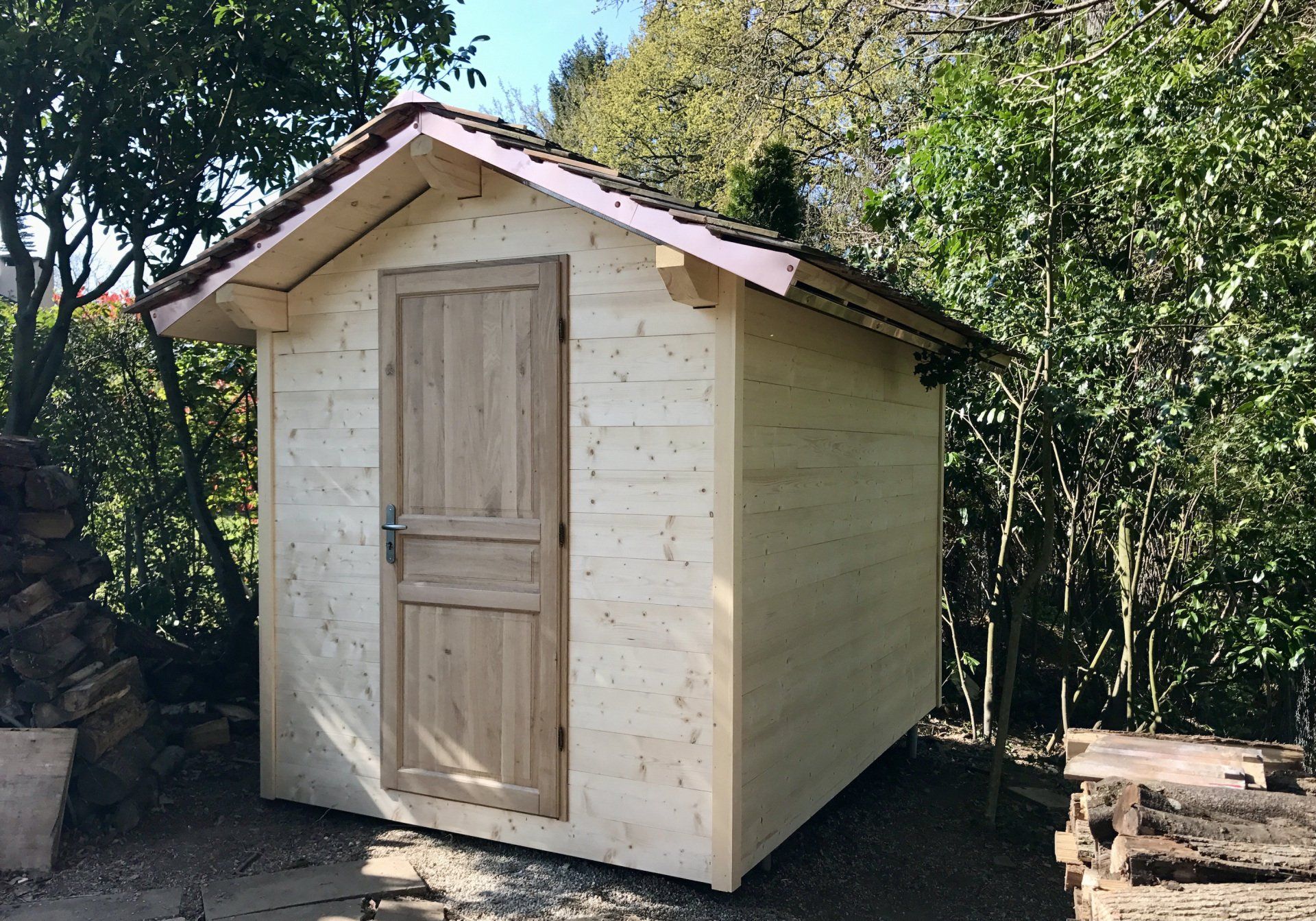 Un petit hangar en bois avec un toit rose est entouré d'arbres.