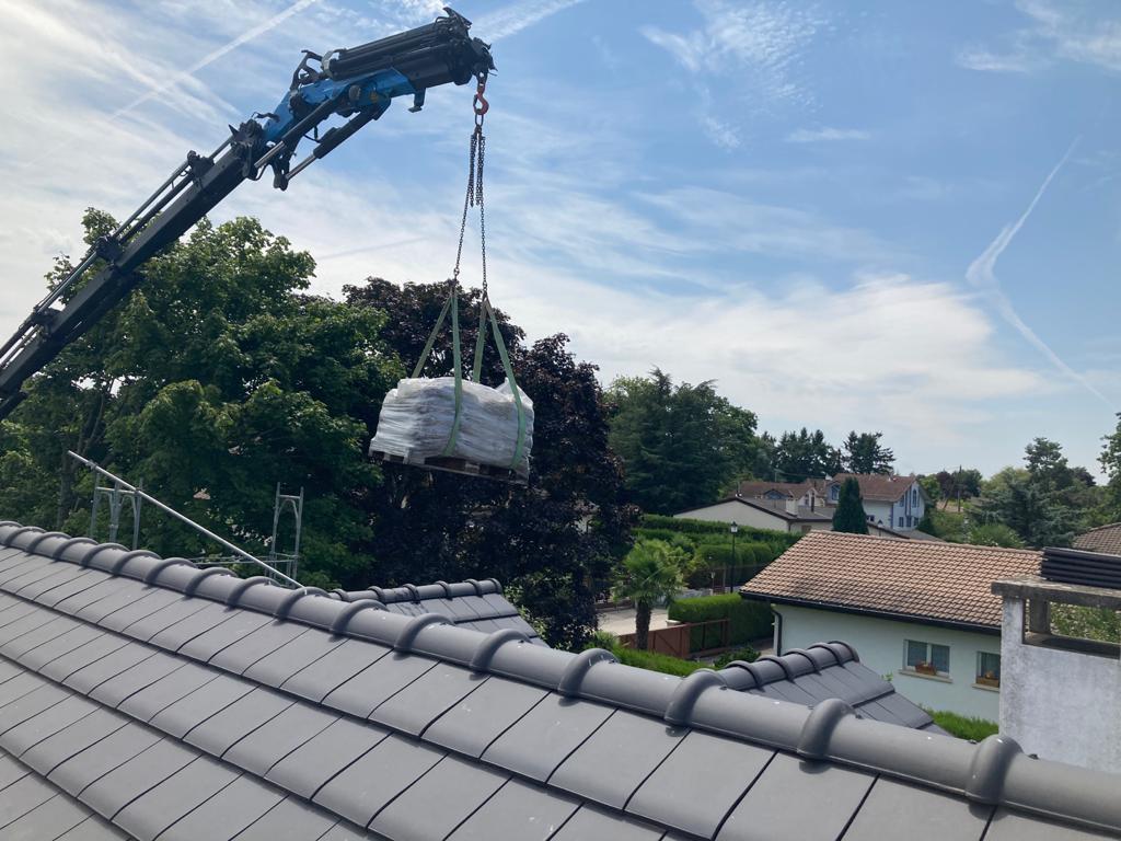 Une grue soulève une palette sur un toit.