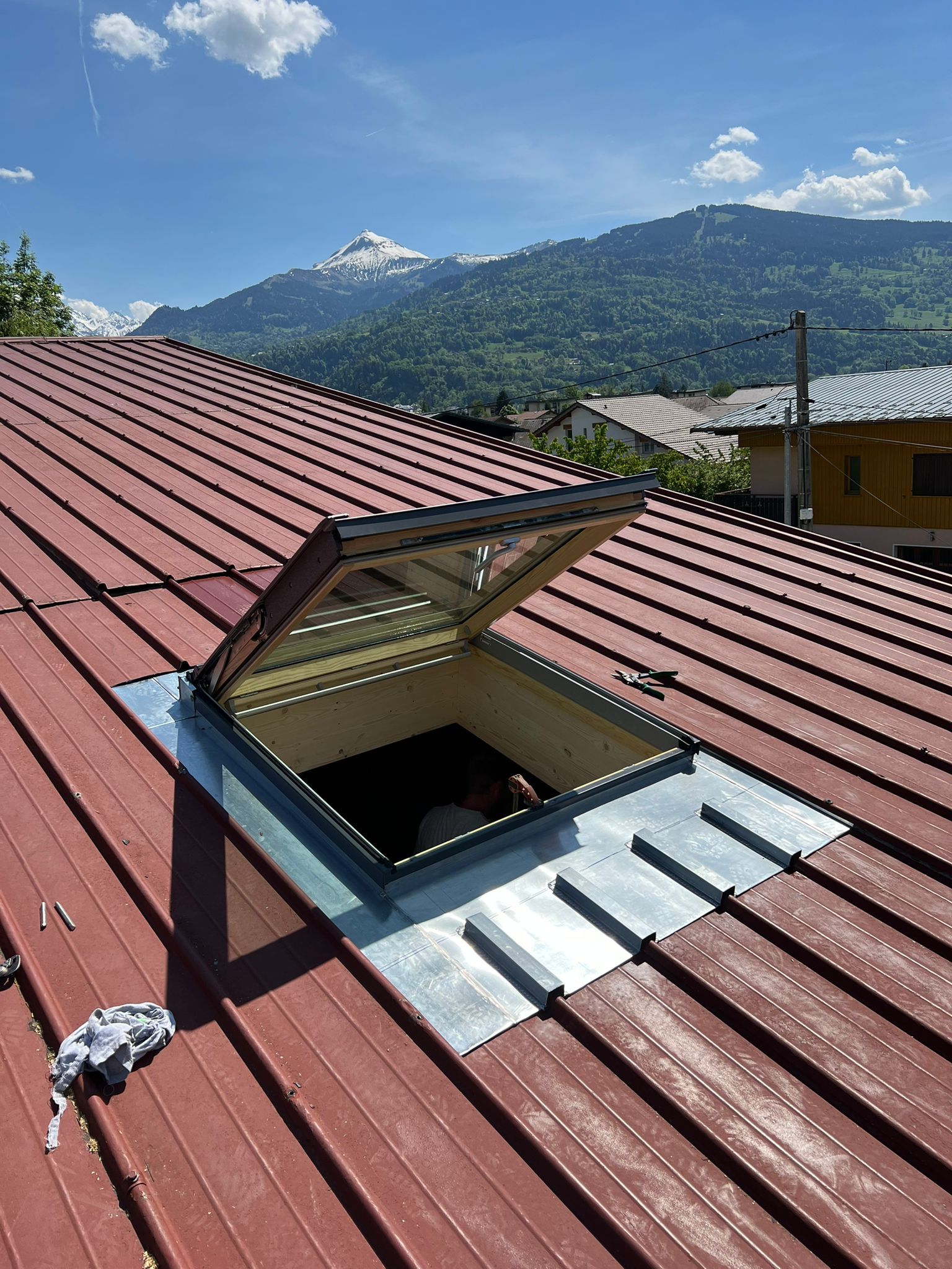 Un toit rouge avec une lucarne et des montagnes en arrière-plan