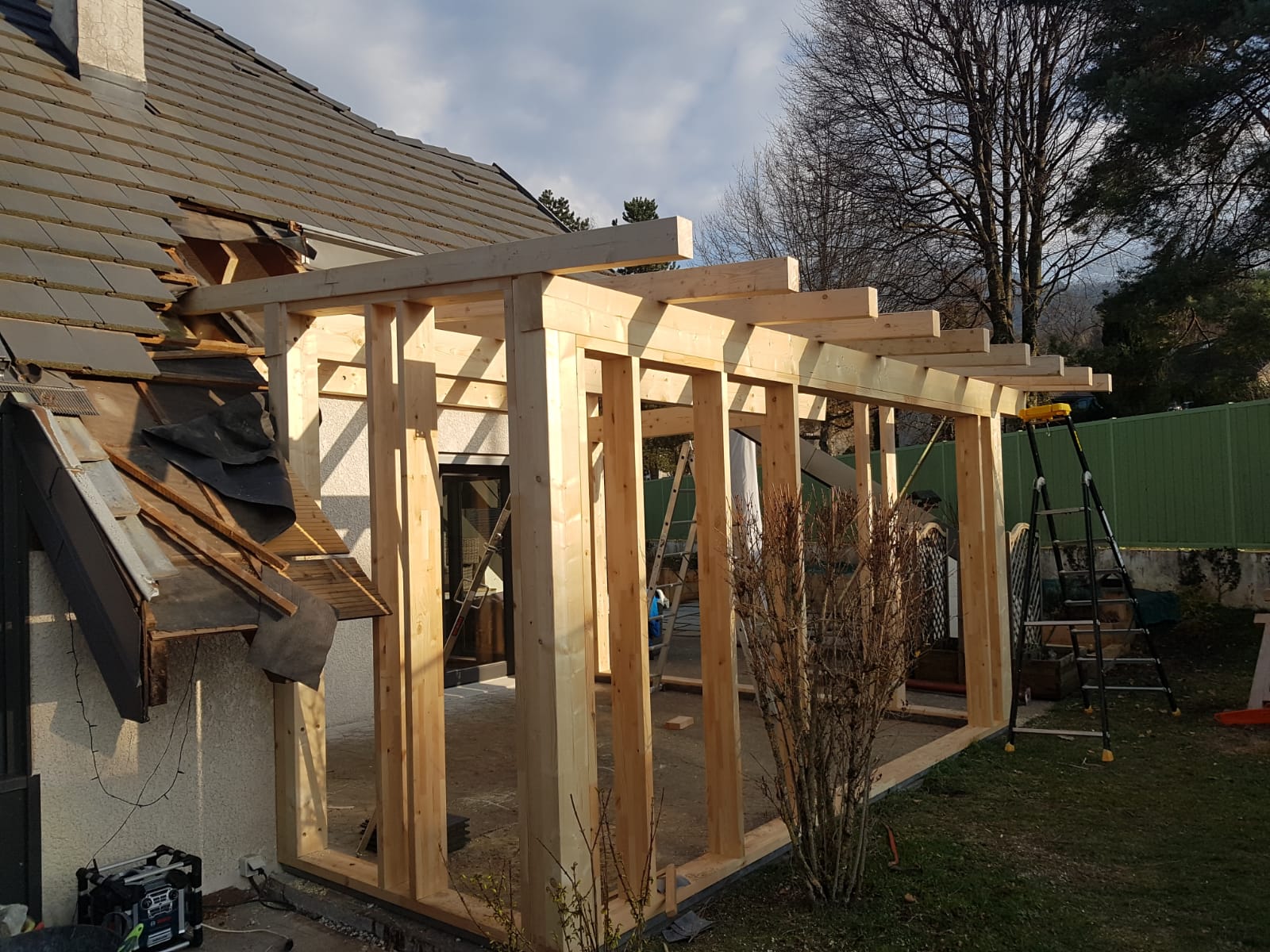 Une structure en bois est en cours de construction sur le côté d'une maison.