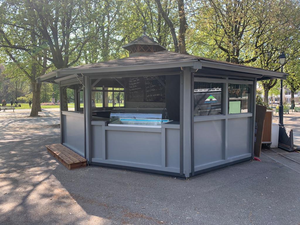Un petit kiosque dans un parc avec des arbres en arrière-plan.