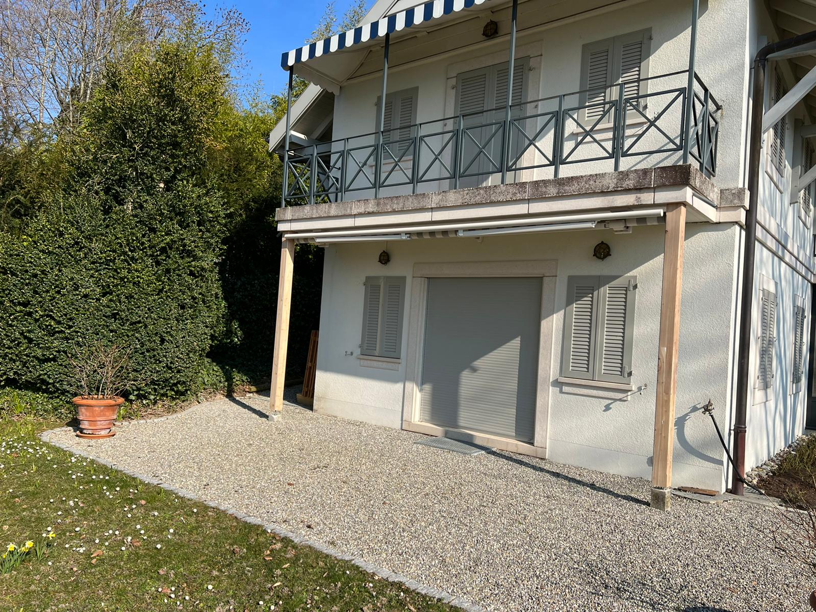 Une maison blanche avec un balcon et une allée devant.