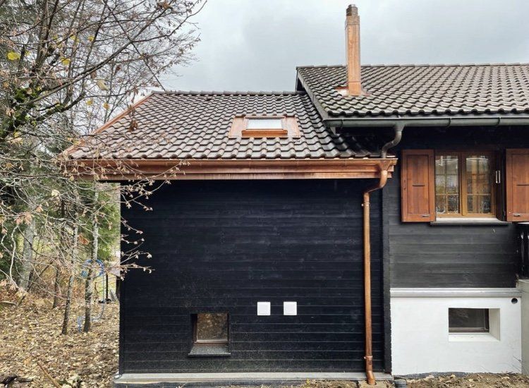 Une maison noire avec un toit marron et une fenêtre
