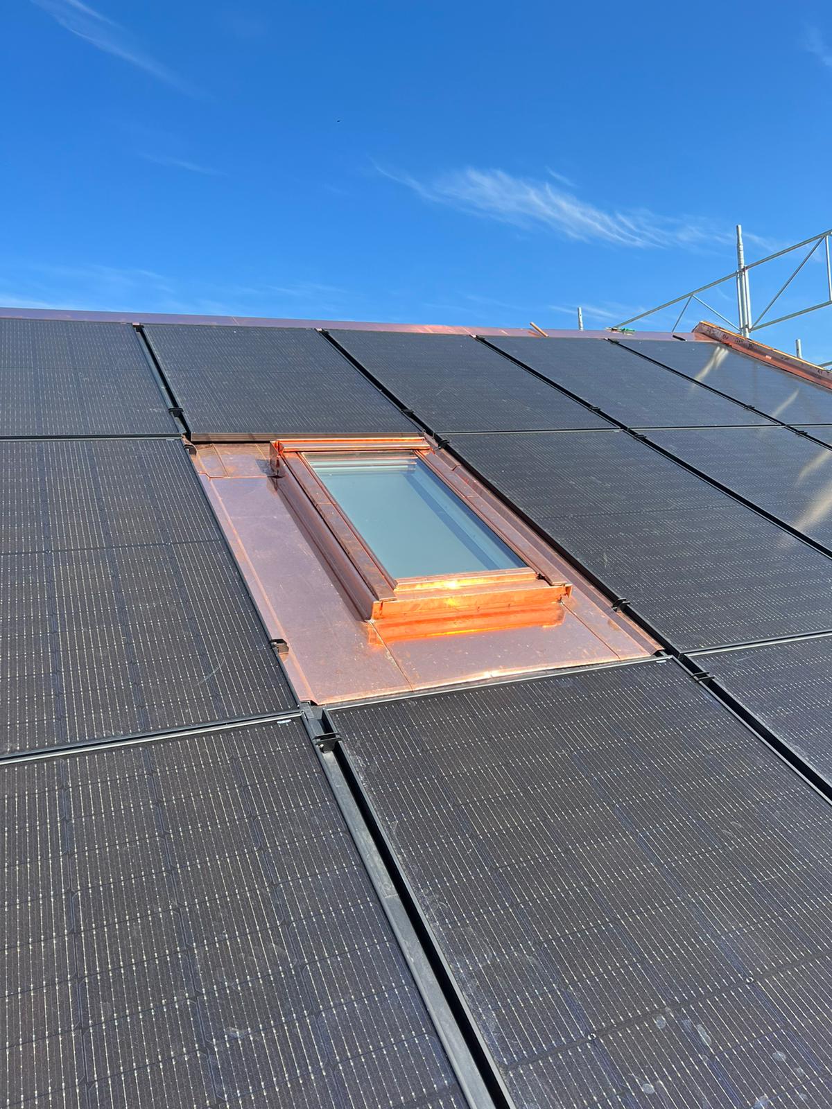 Un toit avec une lucarne et des panneaux solaires dessus.