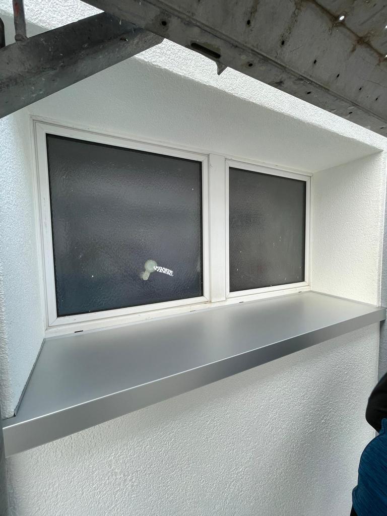 Une personne se tient à côté d'une fenêtre sur un mur blanc.