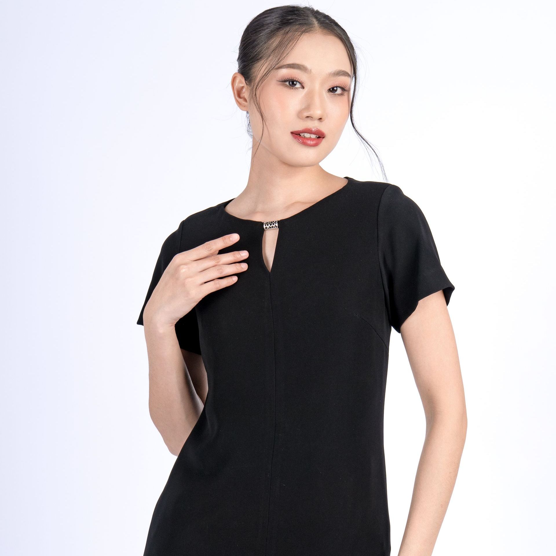 Woman in a black dress with a keyhole neckline, posing against a white background.