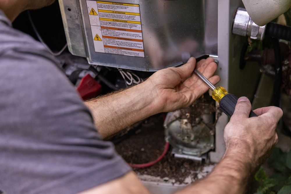 A person using a screwdriver to open or adjust the metal service panel of an outdoor electrical unit.