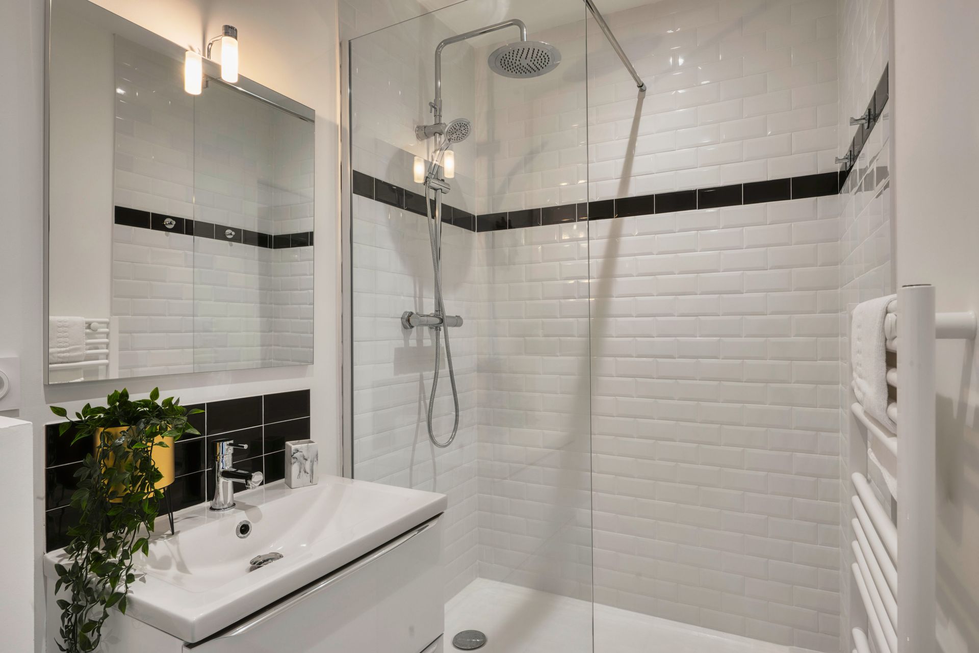 A modern bathroom with a glass shower, white tile walls, and a small sink with a mirror. A modern bathroom with a glass shower, white tile walls, and a small sink with a mirror.