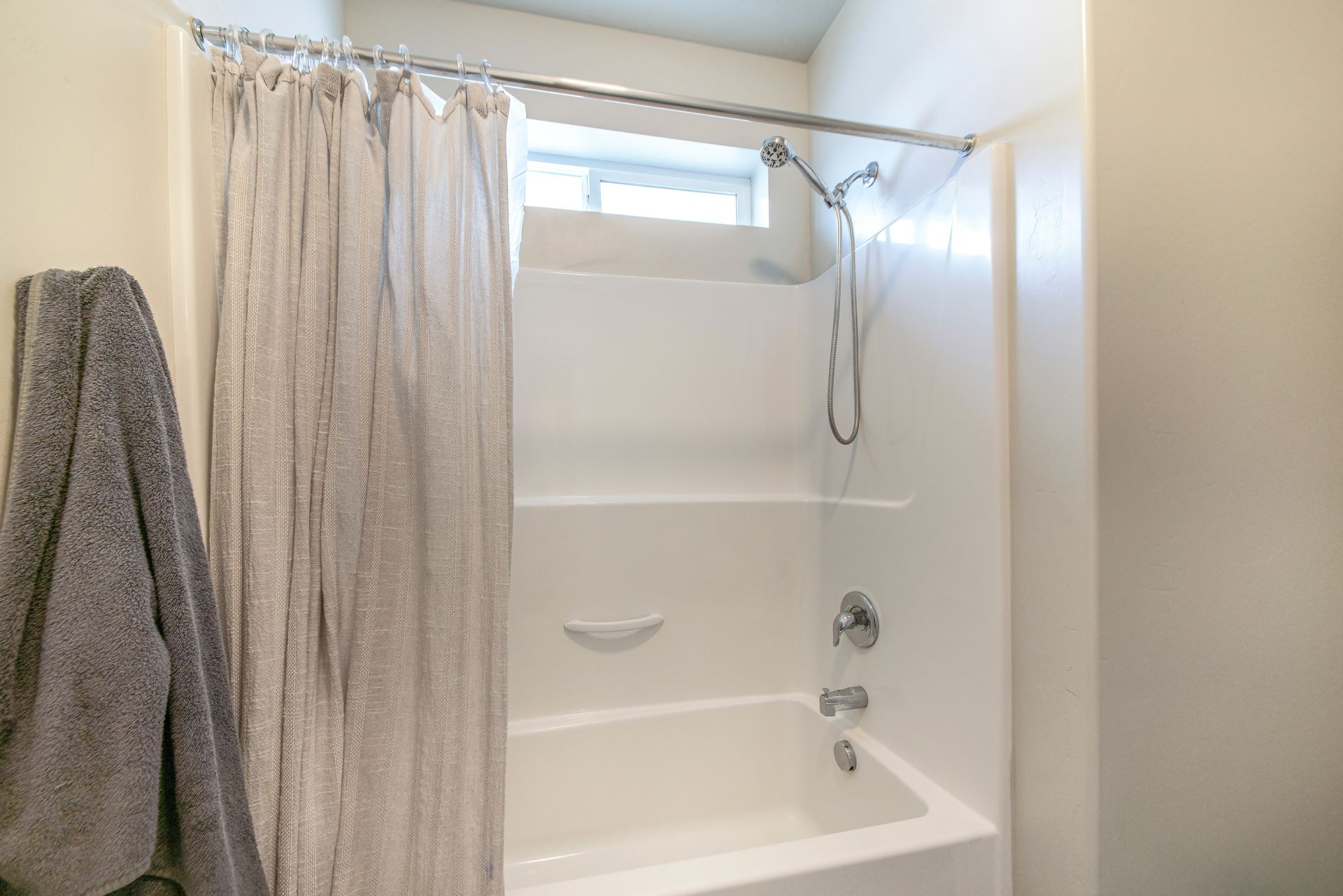 Bathroom interior with tub shower combo and window.