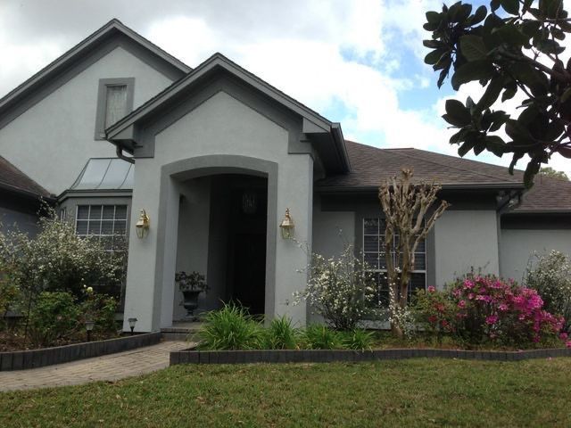 Gray house exterior with arched front entry, white trim, and landscaped front yard