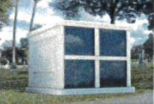 A small white building in a cemetery with trees in the background.