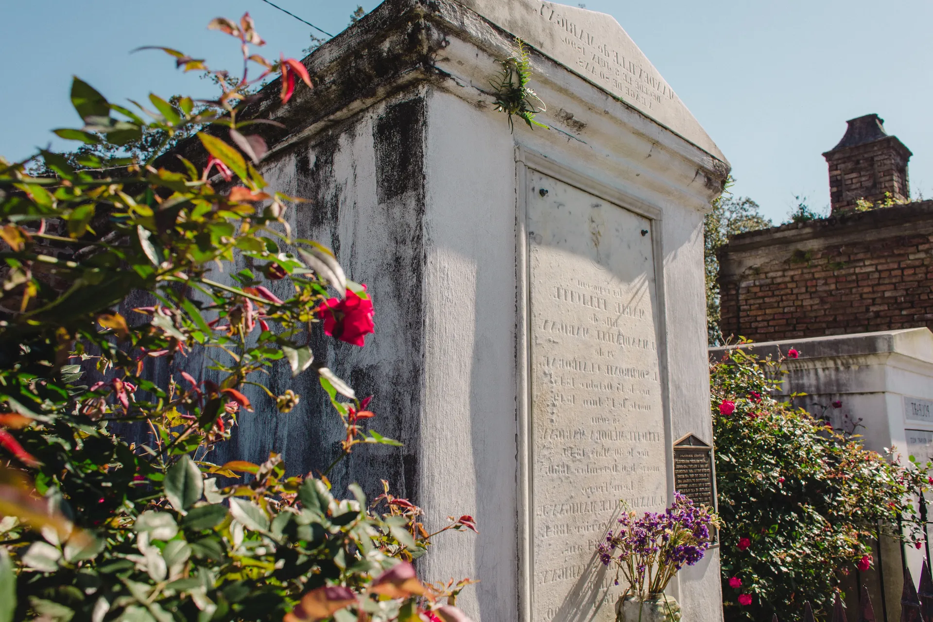 A white building with flowers in front of it in a cemetery.