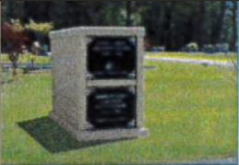 A concrete box is sitting in the grass in a cemetery.