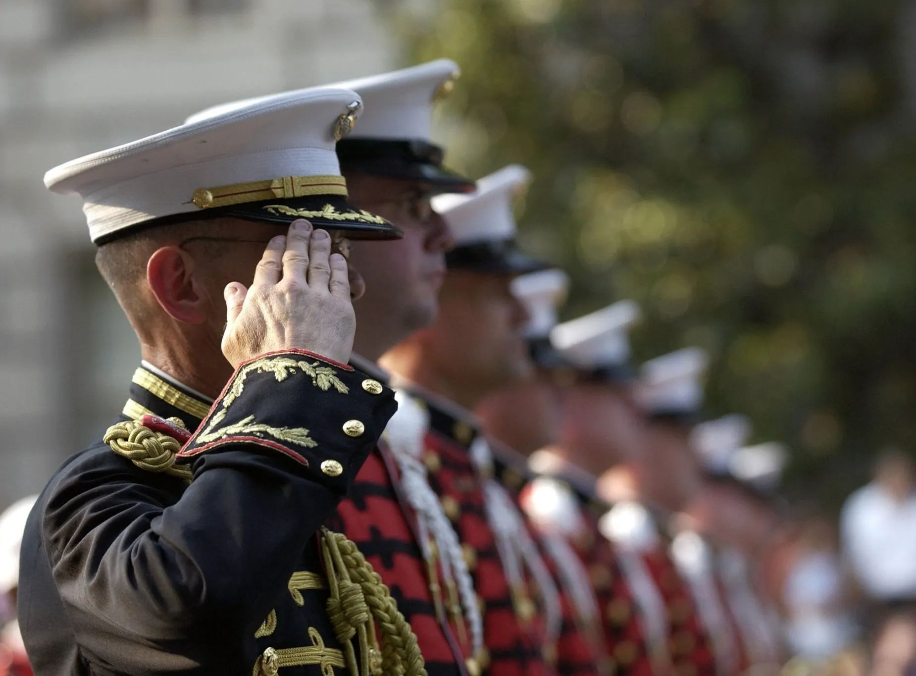 A group of men in military uniforms salute in a line