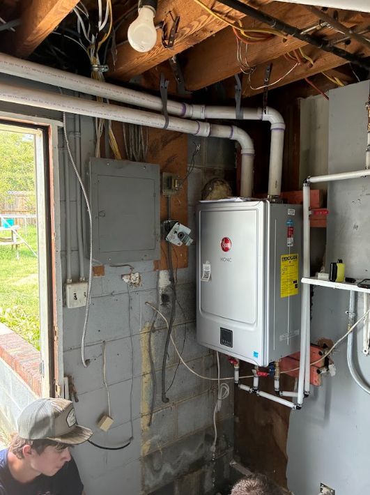 Utility room with exposed wiring, gray electrical panel, white water heater, and open ceiling framing