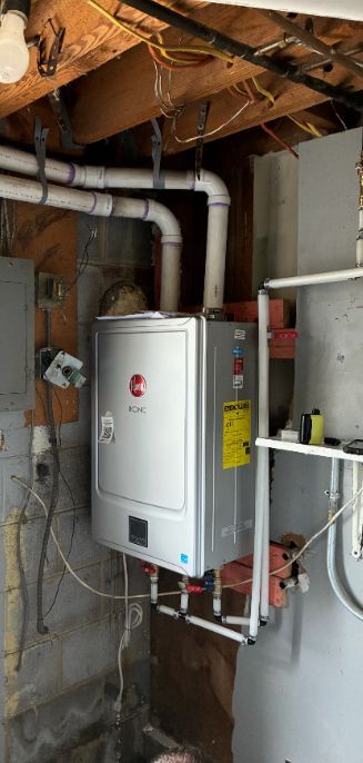Utility room with a wall-mounted water heater, exposed pipes, and unfinished ceiling framing