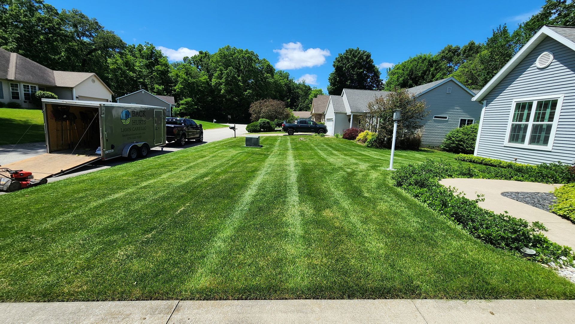 A lush green lawn in front of a house on a sunny day.