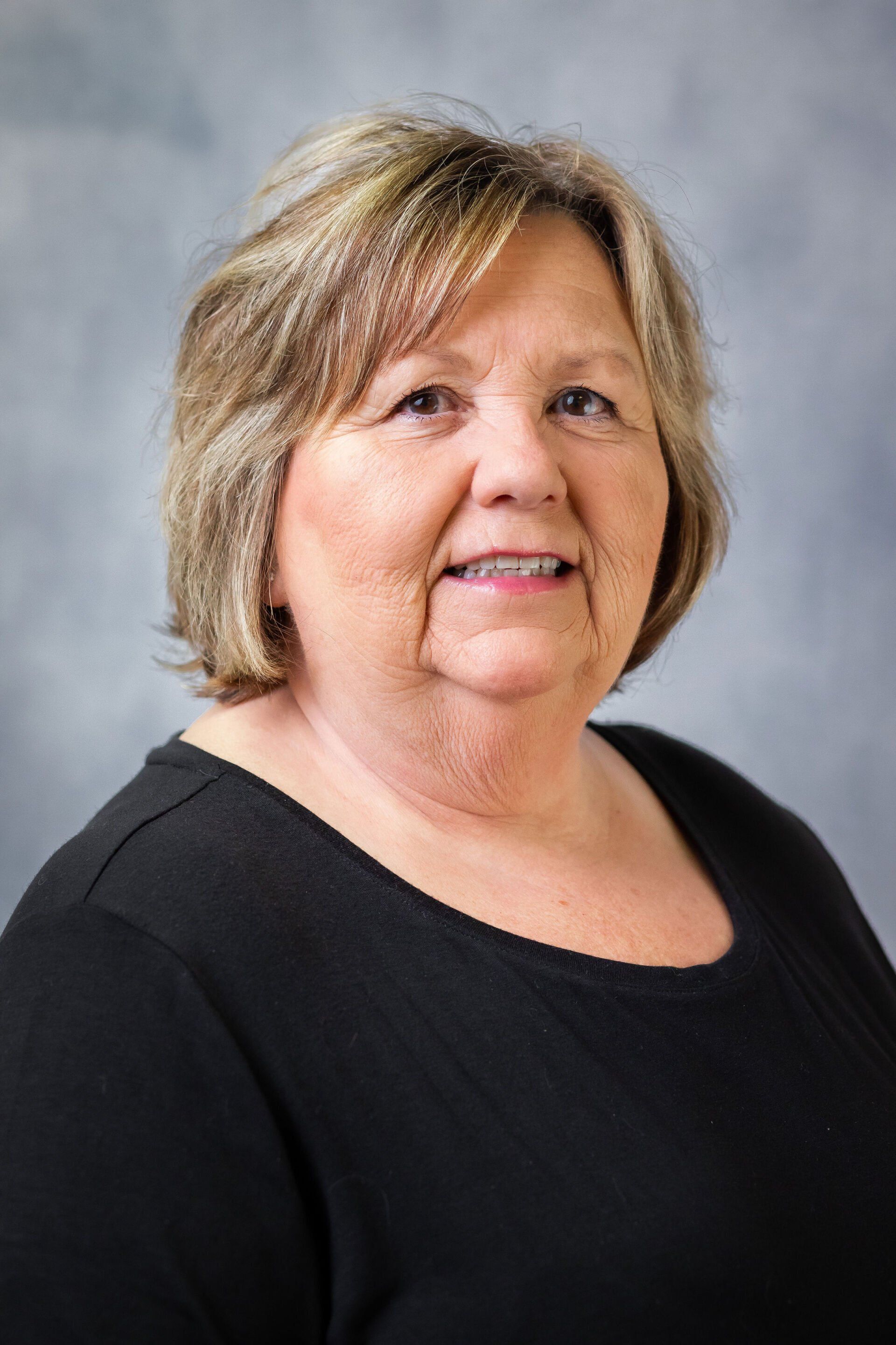 A woman in a black shirt is smiling for the camera.