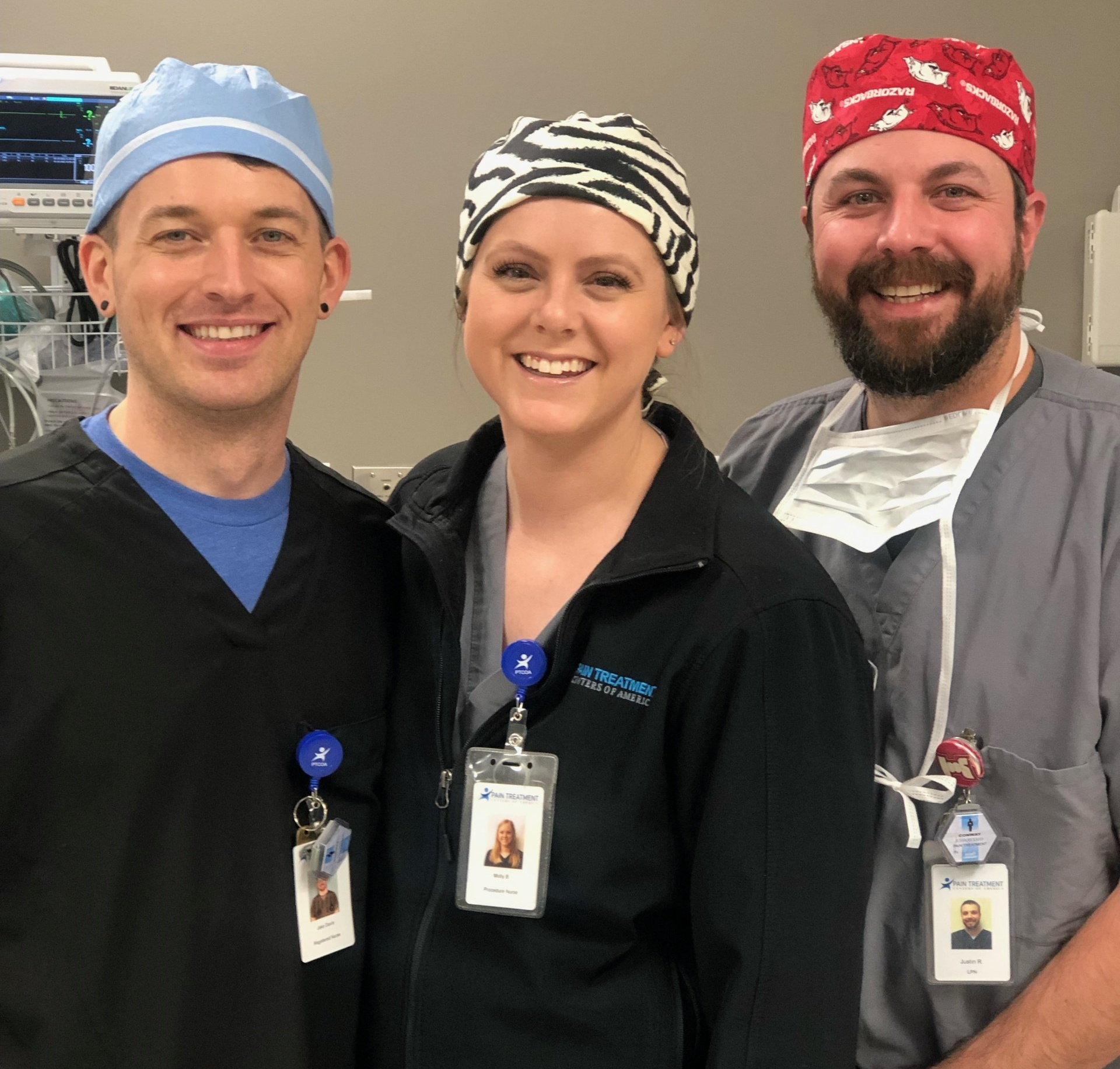 Three doctors are posing for a picture in an operating room