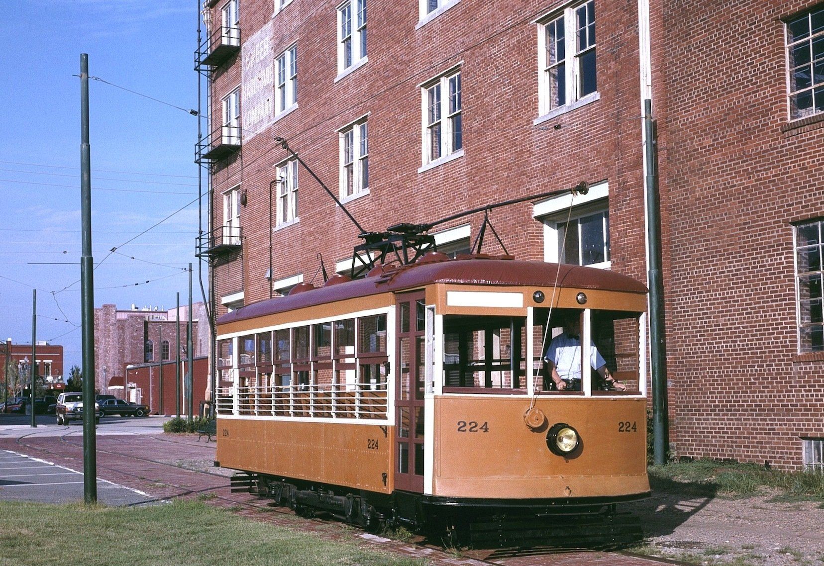 A trolley is parked in front of a brick building
