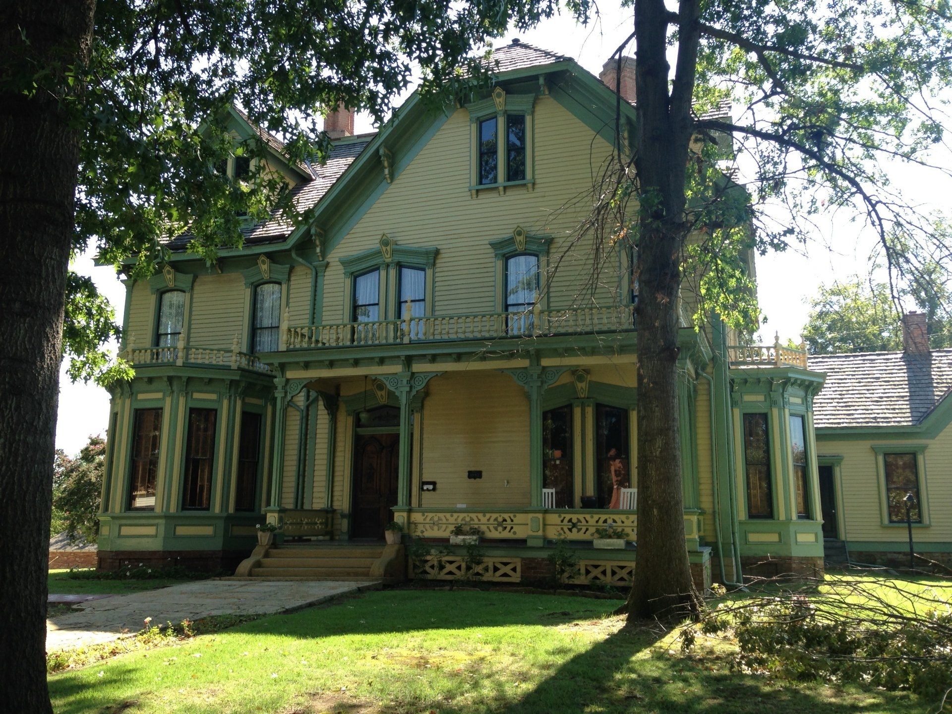 A large house with a porch is surrounded by trees