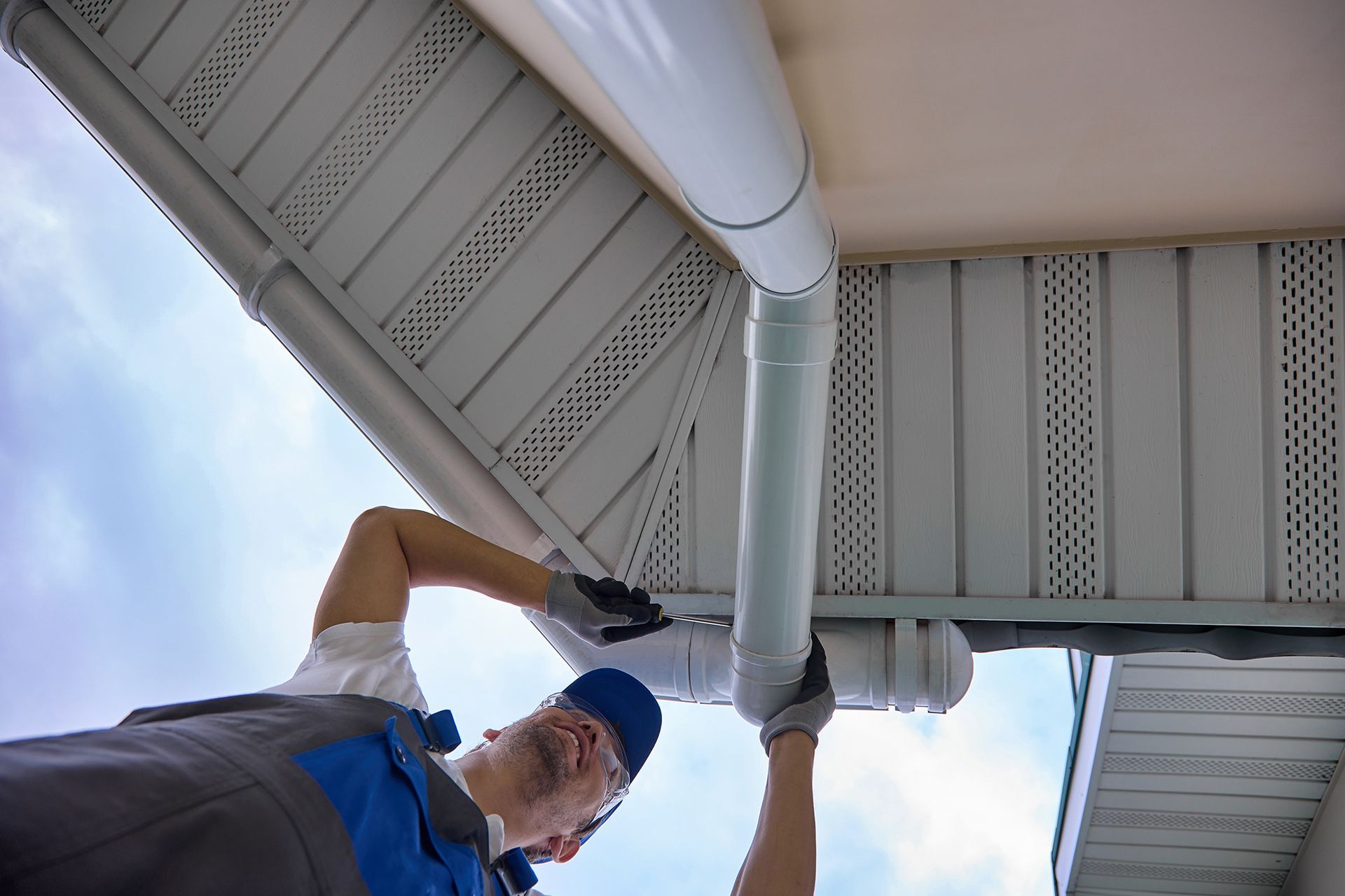 A man is fixing a gutter on the roof of a building.