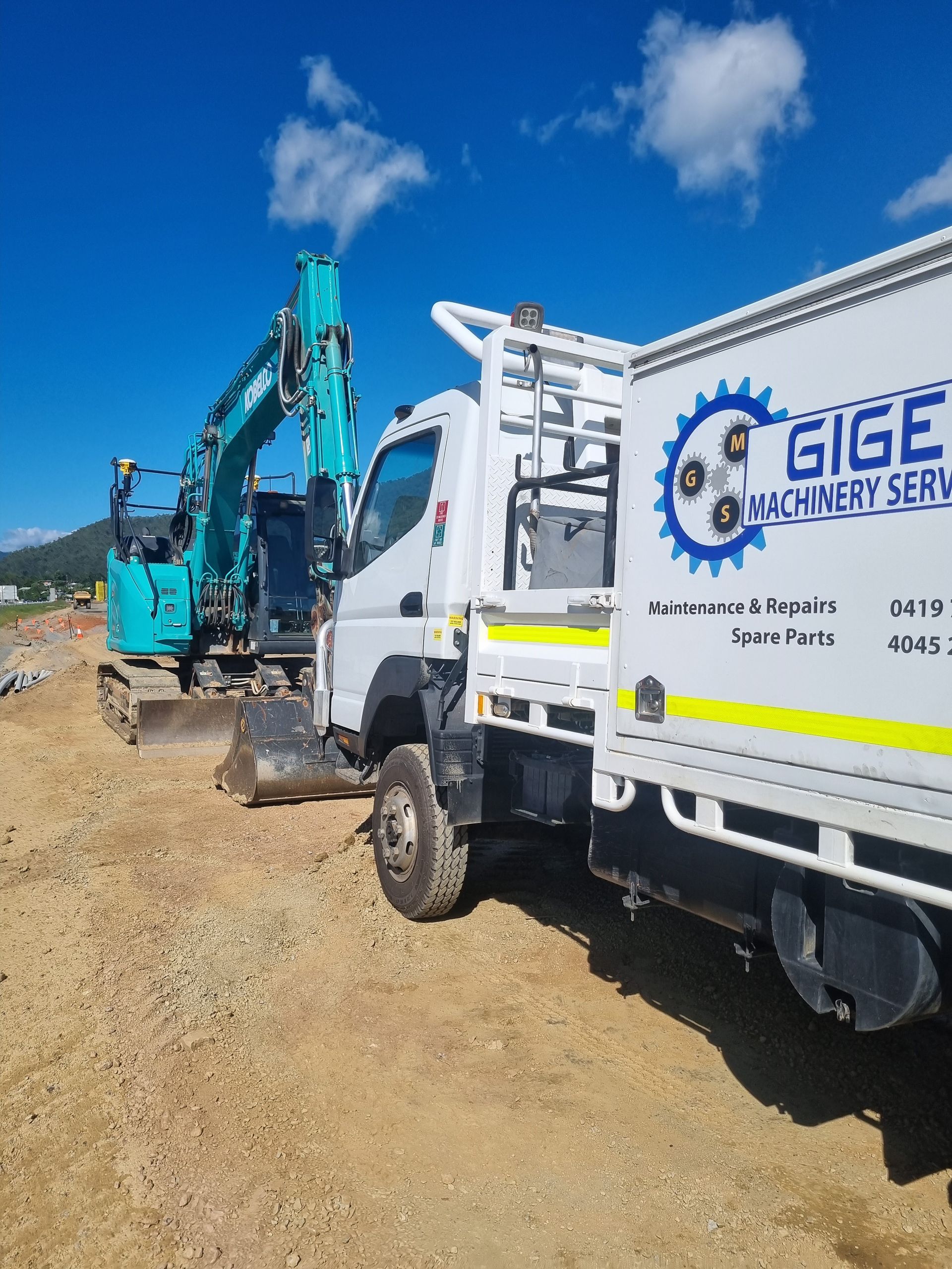 A White Truck is Parked Next to a Green Excavator on a Dirt Road — Giger Machinery Services in Bentley Park, QLD