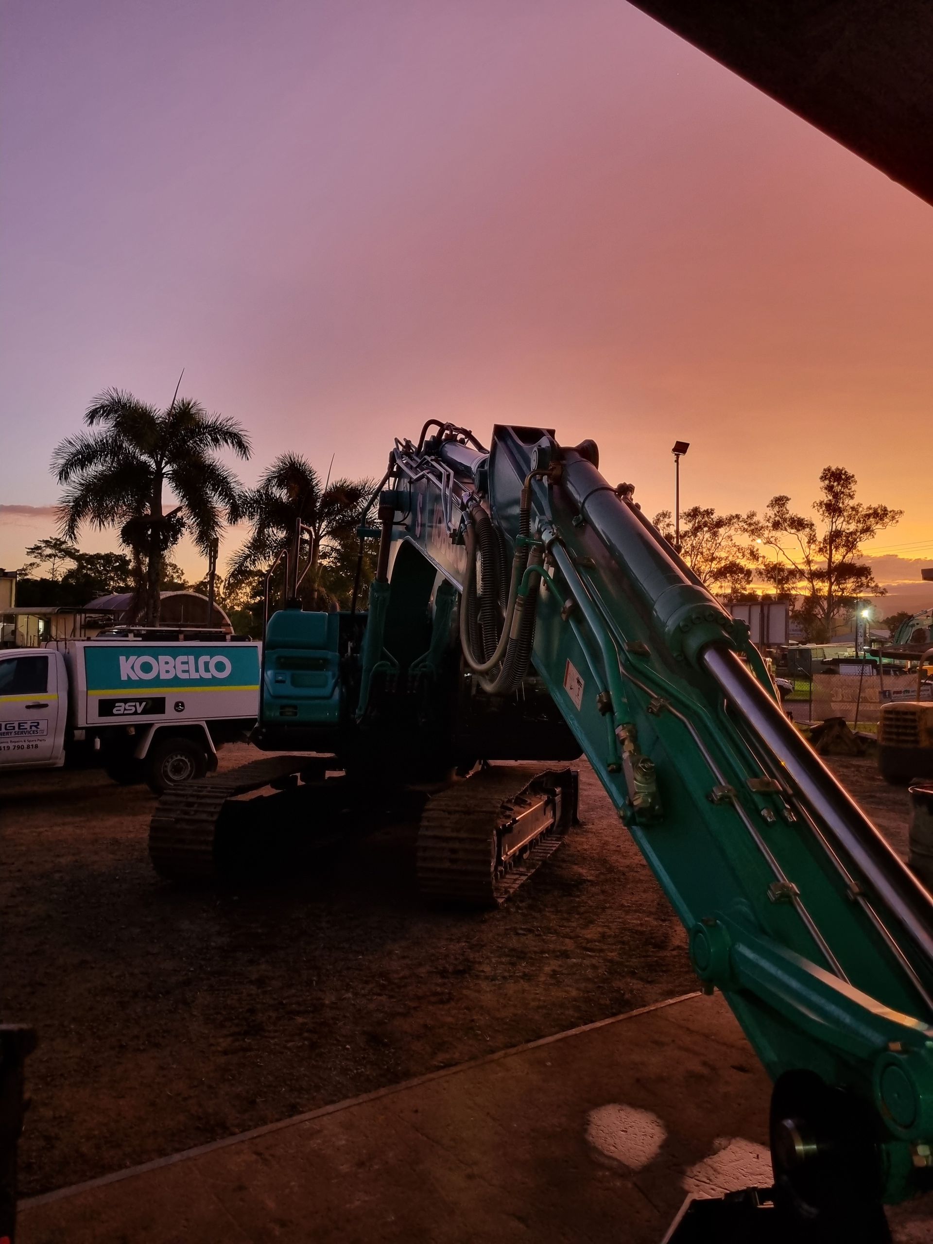 A Komatsu Excavator is Parked in a Parking Lot at Sunset — Giger Machinery Services in Bentley Park, QLD