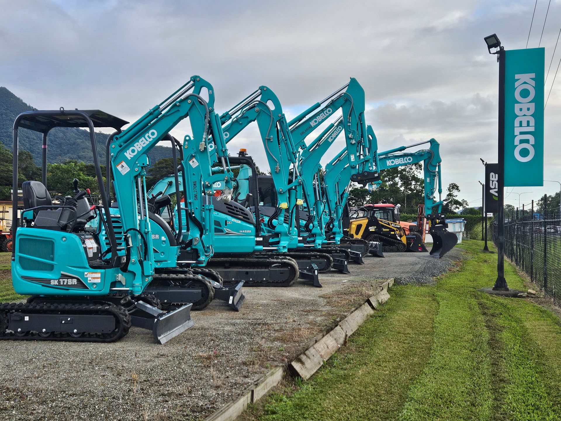 A Row of Kobelco Excavators Are Parked in a Gravel Lot — Giger Machinery Services in Bentley Park, QLD