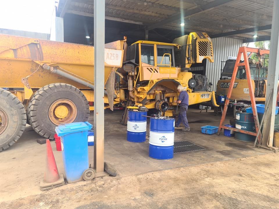 A Man is Working on a Yellow Dump Truck in a Garage — Giger Machinery Services in Bentley Park, QLD