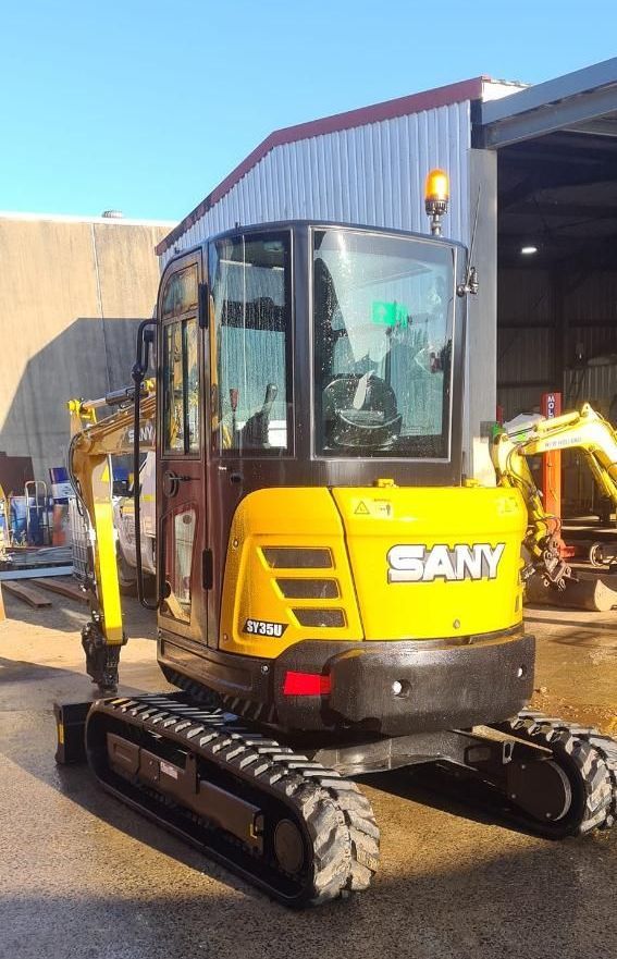 A Yellow Excavator is Parked in Front of a Building — Giger Machinery Services in Bentley Park, QLD