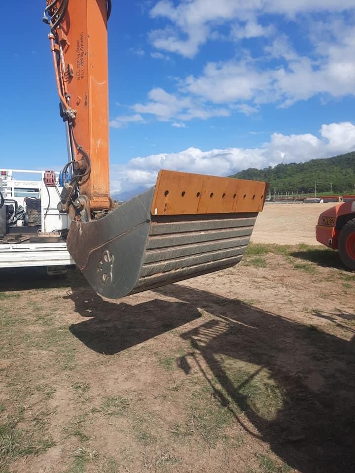 A Large Excavator Bucket is Sitting on Top of a Dirt Field — Giger Machinery Services in Bentley Park, QLD