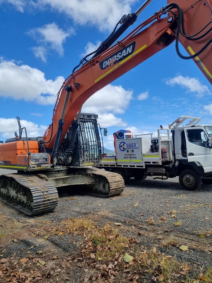 A Large Excavator is Parked Next to a Truck — Giger Machinery Services in Gordonvale, QLD