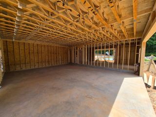 Unfinished wooden room interior with exposed framing, plywood walls, and a concrete floor.
