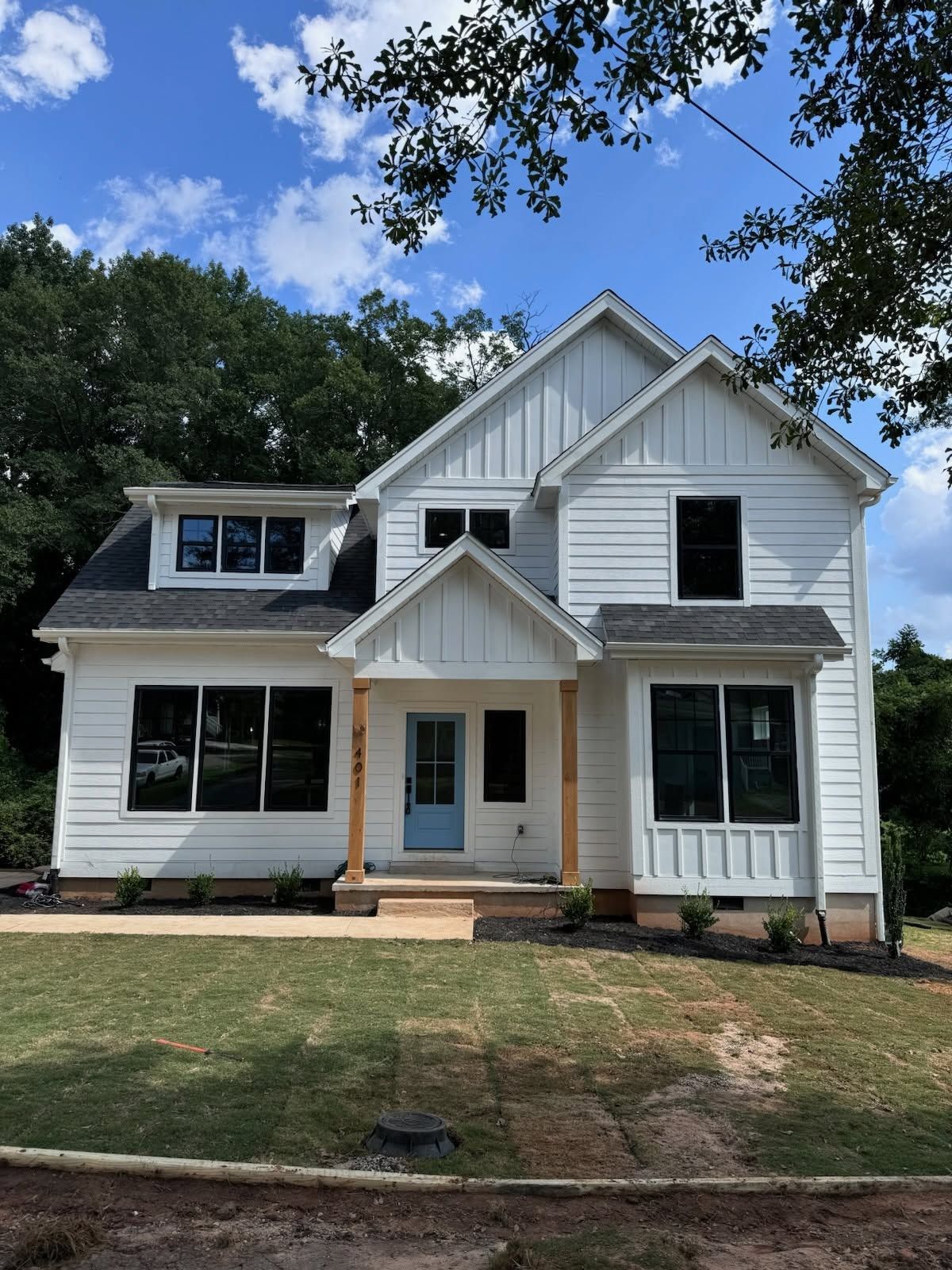White two-story house with black shutters and a small front porch under a blue sky