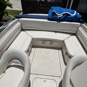 Interior of a boat with cream-colored seating. There's a back bench, side seats, and front captain's chairs, all in the same neutral color. Interior of a boat with cream-colored seating. There's a back bench, side seats, and front captain's chairs, all in the same neutral color.
