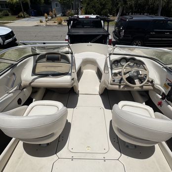 Interior view of a white motorboat with two seats, a dashboard, and a windshield. The boat is outdoors on a sunny day. Interior view of a white motorboat with two seats, a dashboard, and a windshield. The boat is outdoors on a sunny day.
